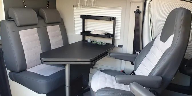 Bild zeigt einen Essbereich in einem Wohnmobil mit drehbaren Fahrer- und Beifahrersitz